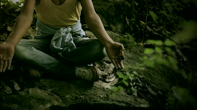 Young man doing meditation yoga in woods.